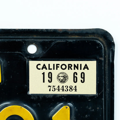 California license plate 1969 year sticker applied to upper corner of black California plate — YOM Series