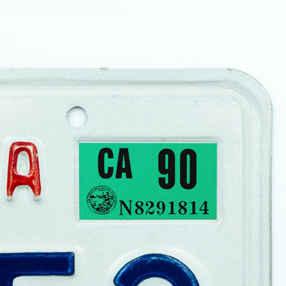 California license plate 1990 year sticker applied to upper corner of white California plate — Classic Series