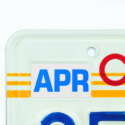 California license plate April month sticker applied to upper corner of 1980s sunset California plate — Blue Series