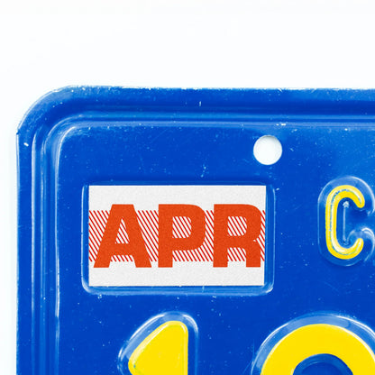California license plate April month sticker applied to upper corner of blue California plate — Red Series