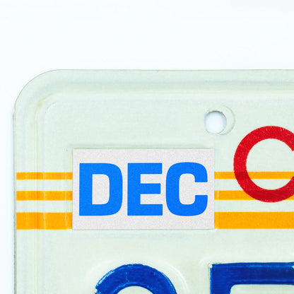 California license plate December month sticker applied to upper corner of 1980s sunset California plate — Blue Series