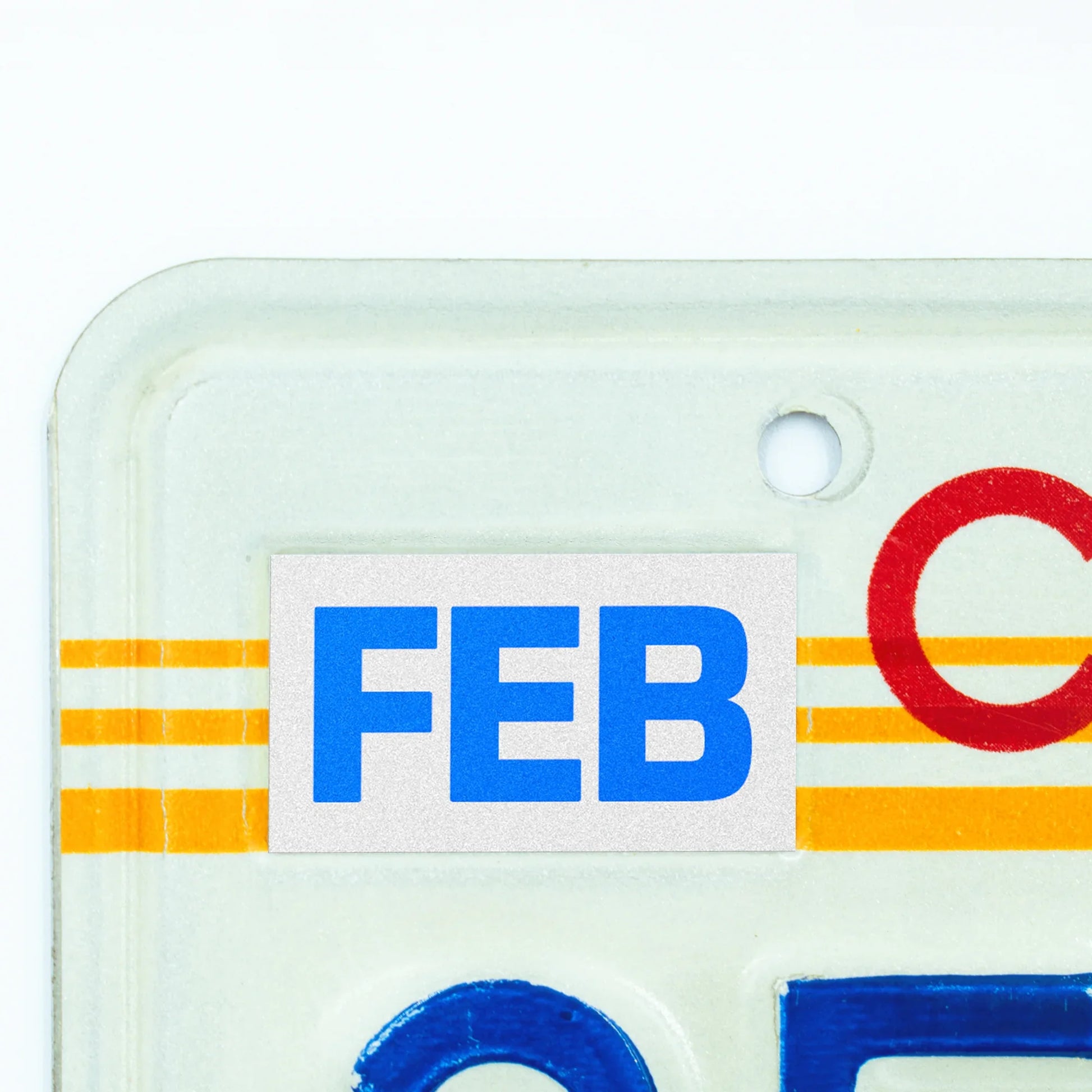 California license plate February month sticker applied to upper corner of 1980s sunset California plate — Blue Series