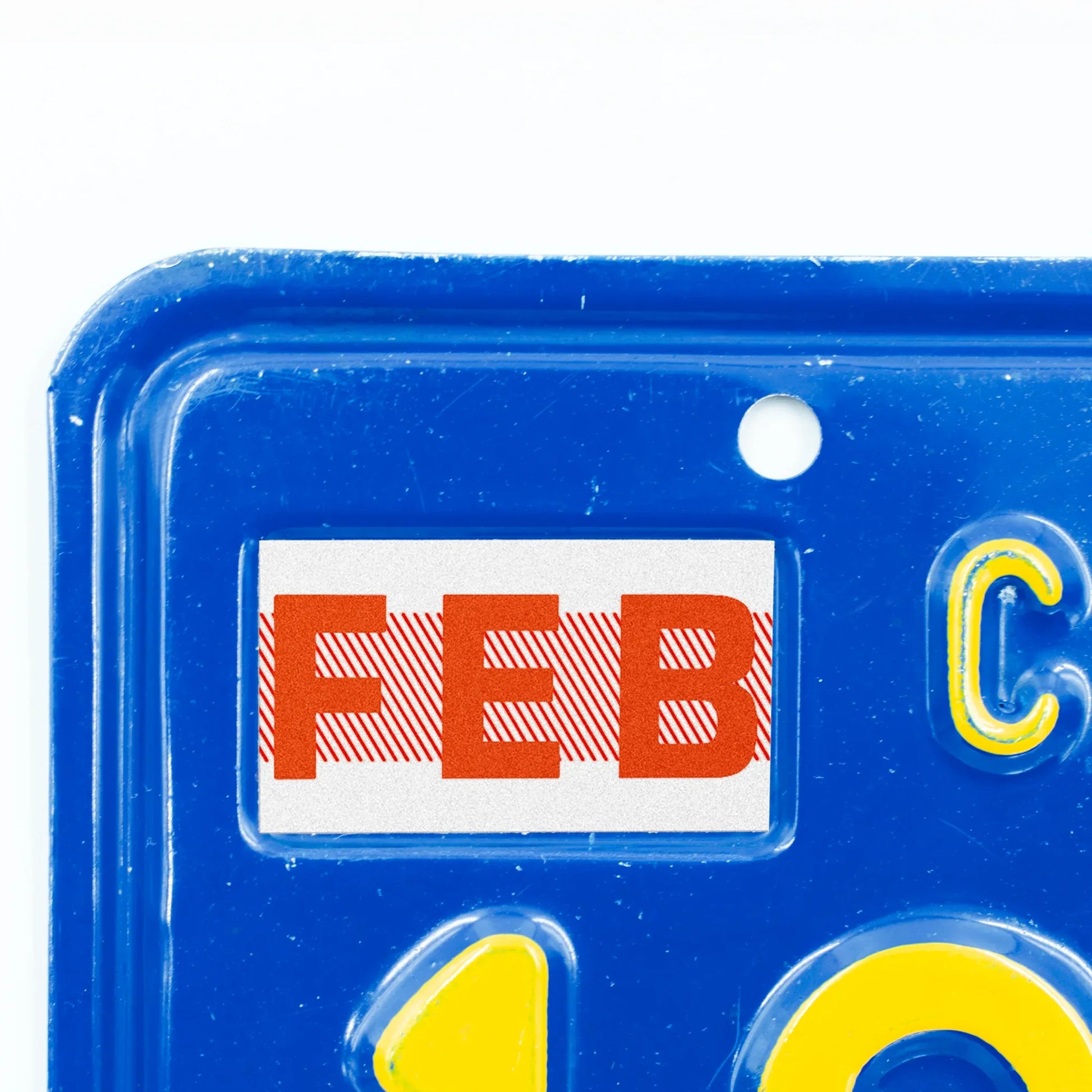 California license plate February month sticker applied to upper corner of blue California plate — Red Series