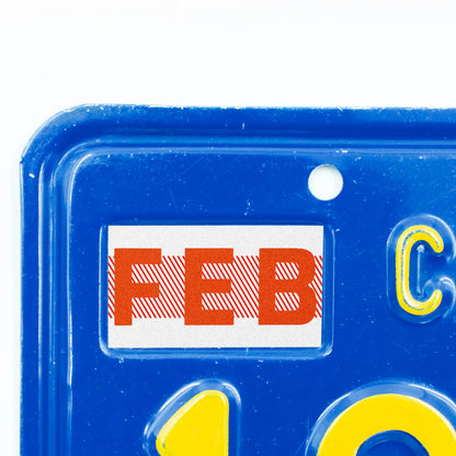 California license plate February month sticker applied to upper corner of blue California plate — Red Series