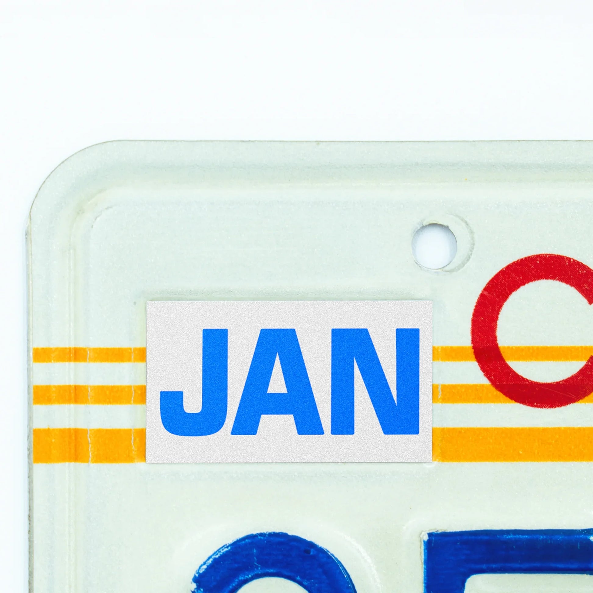 California license plate January month sticker applied to upper corner of 1980s sunset California plate — Blue Series