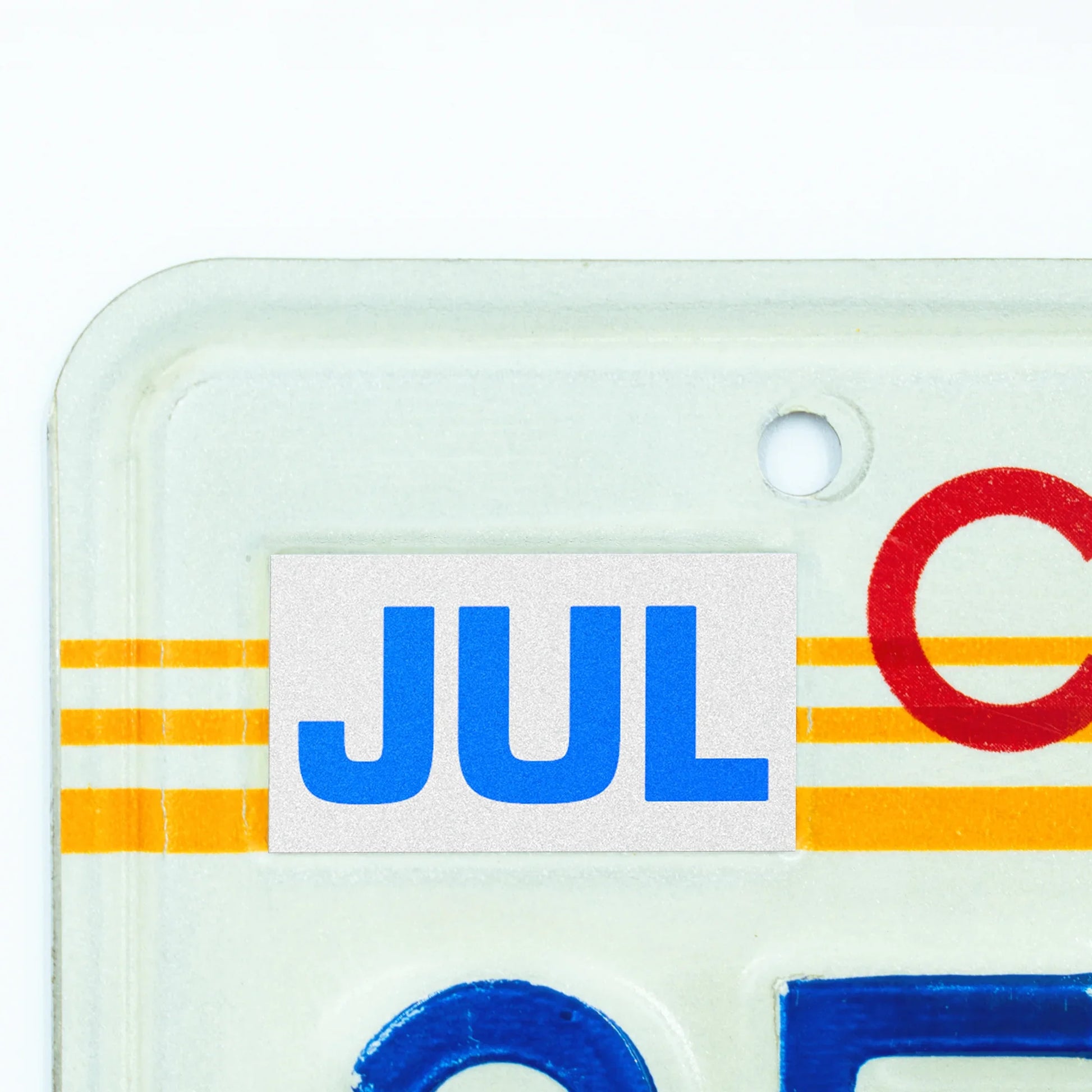 California license plate July month sticker applied to upper corner of 1980s sunset California plate — Blue Series