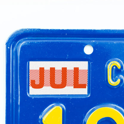California license plate July month sticker applied to upper corner of blue California plate — Red Series