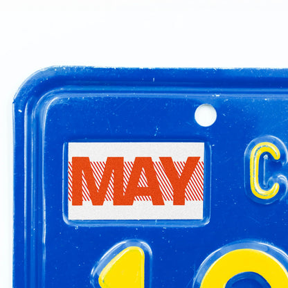 California license plate May month sticker applied to upper corner of blue California plate — Red Series