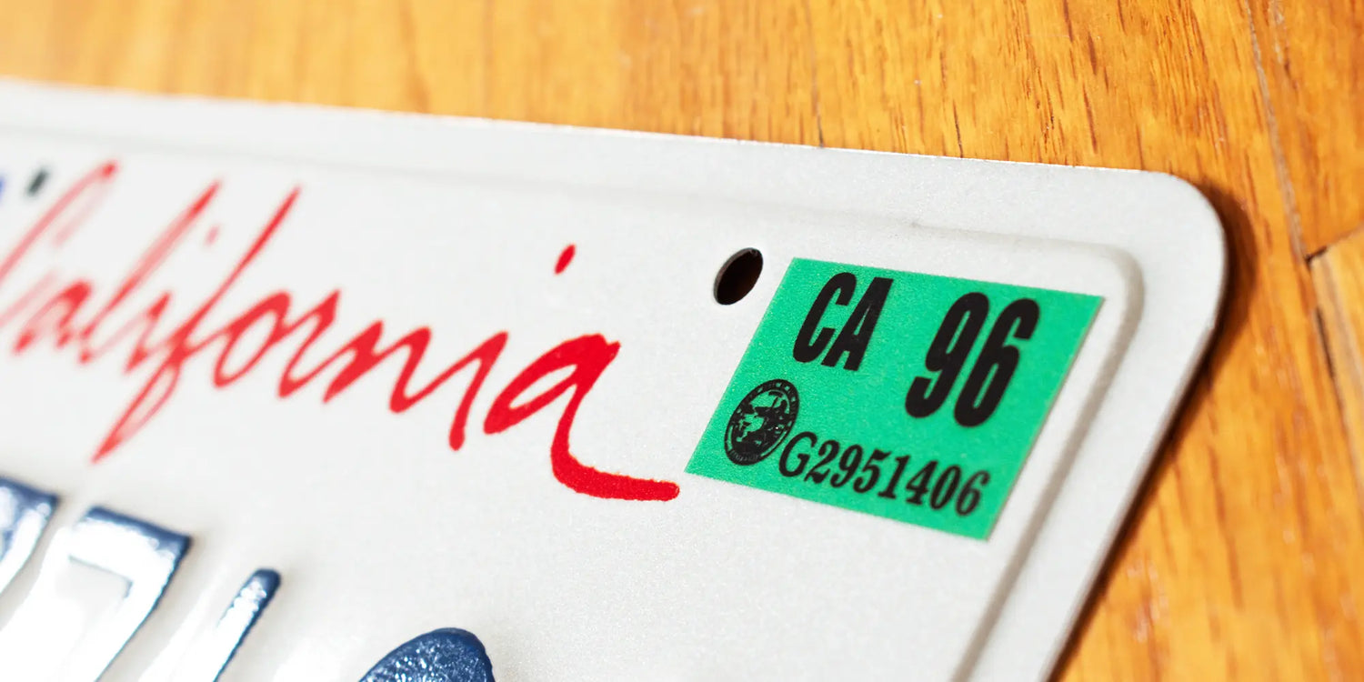 California license plate with 1996 green registration year sticker (CA 96) on wooden background